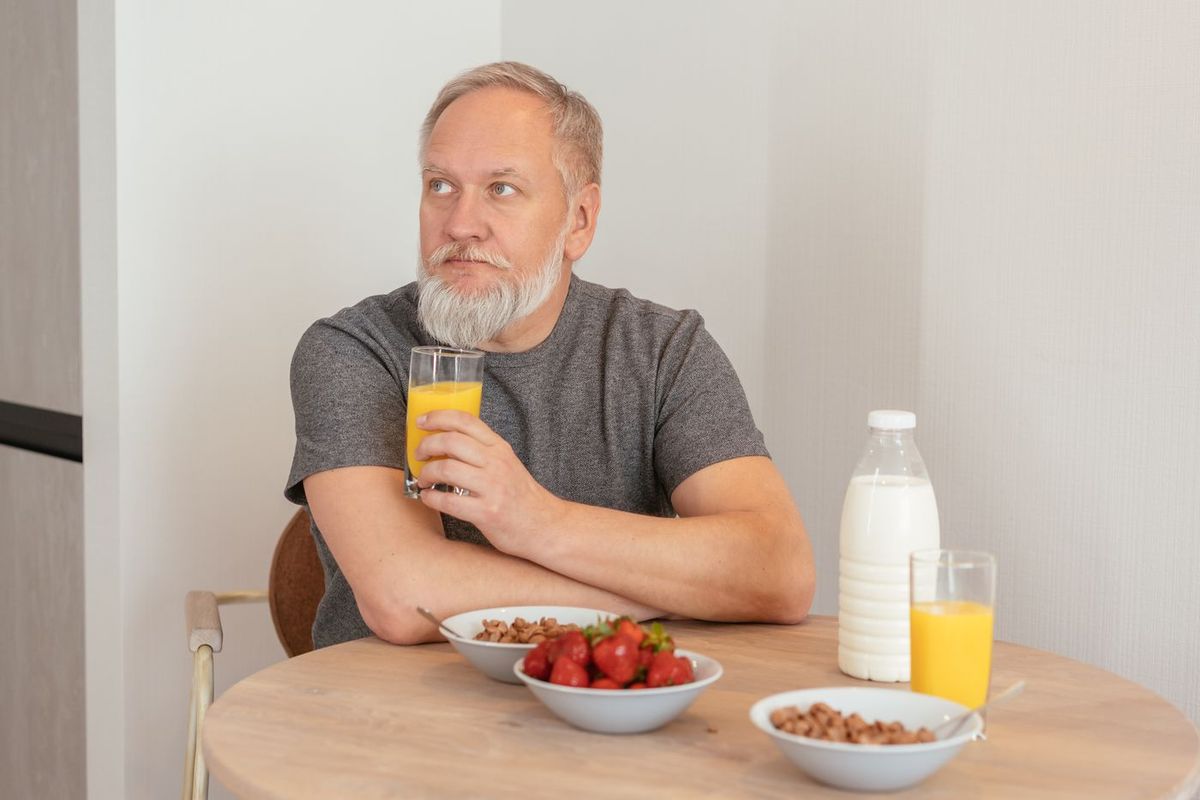 Man vid köksbordet med ett glas och en frukost